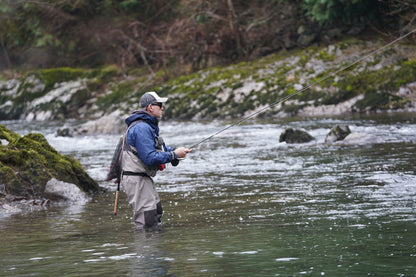Fly angler fishing beside a rocky riverbank